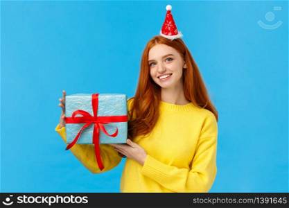 Waist-up portrait young cute redhead caucasian female celebrating christmas holidays, new year party, exchanching gifts with friends during secret santa, holding box of present, wear fancy hat.. Waist-up portrait young cute redhead caucasian female celebrating christmas holidays, new year party, exchanching gifts with friends during secret santa, holding box of present, wear fancy hat
