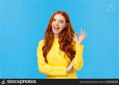 Waist-up shot carefree cheerful and friendly redhead gorgeous female freelancer finished IT school and showing okay gesture, no problem sign, smiling unbothered, assure all good, blue background.. Waist-up shot carefree cheerful and friendly redhead gorgeous female freelancer finished IT school and showing okay gesture, no problem sign, smiling unbothered, assure all good, blue background