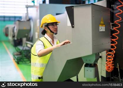Waist up woman worker with hardhat and protection glasses press keyboard of monitor screen and console to command automate robot machine in factory workshop. Manufacturing industry with technology.