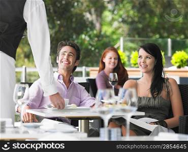 Waiter bringing coffee to couple at outdoor cafe