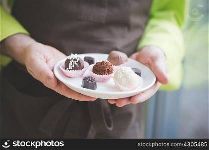 Waiter carrying plate of varying confectionery