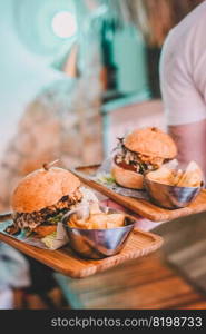 Waiter carrying two cheeseburgers and fries