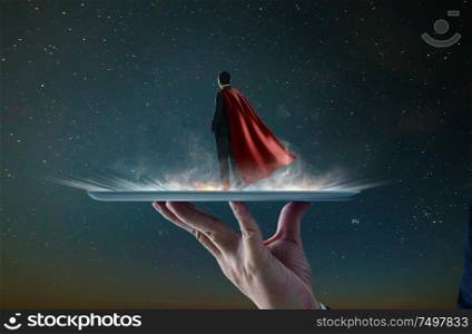 Waiter hand holding an empty digital tablet with Businessman in a suit and cape hero ,victory concept.