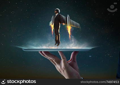 Waiter hand holding an empty digital tablet with Businessman wear a rocket suit to lift , Business success concept .