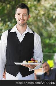 Waiter holding slice of pie at outdoor cafe