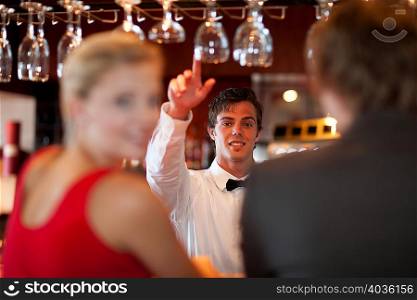 Waiter offering more drinks at bar