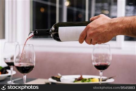 Waiter pouring red wine into wineglass