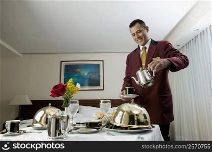 Waiter pouring tea in a cup