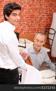 Waiter serving a bottle of rose to a male diner in a restaurant