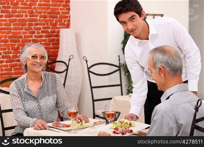 Waiter serving a senior couple