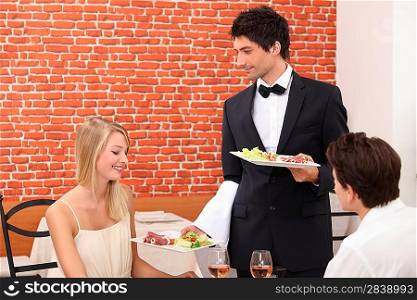 Waiter serving couple in restaurant