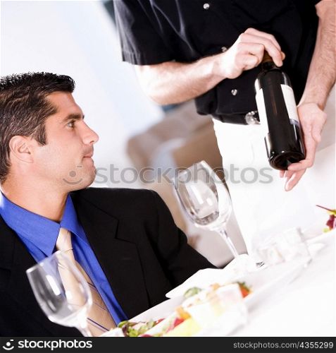 Waiter showing a mid adult man a wine bottle