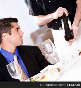 Waiter showing a wine bottle to a mid adult man