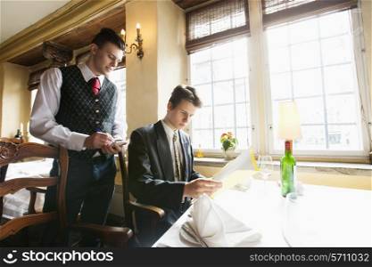 Waiter taking businessman&rsquo;s order at restaurant
