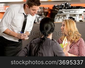 Waiter taking orders from young woman customer in restaurant