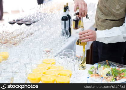 waiter unscrews cork from wine bottle before pouring . unscrewing cork