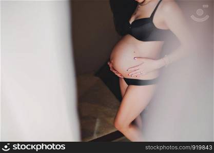 Waiting baby. Pregnant woman standing and hands embraces a round belly, stomach. close-up. nine months. Baby Shower. Motherhood concept. side view.. Waiting baby. Pregnant woman standing and hands embraces a round belly, stomach. close-up. Motherhood concept.