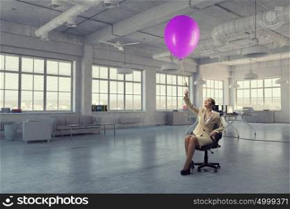 Waiting for inspiration to come. Young businesswoman sitting in chair with color balloon in hand