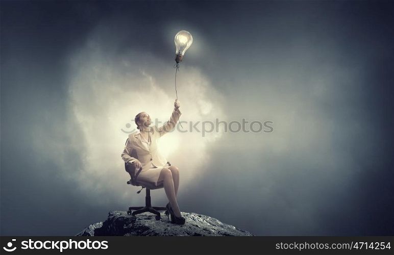 Waiting for inspiration to come. Young businesswoman sitting in chair with light bulb balloon