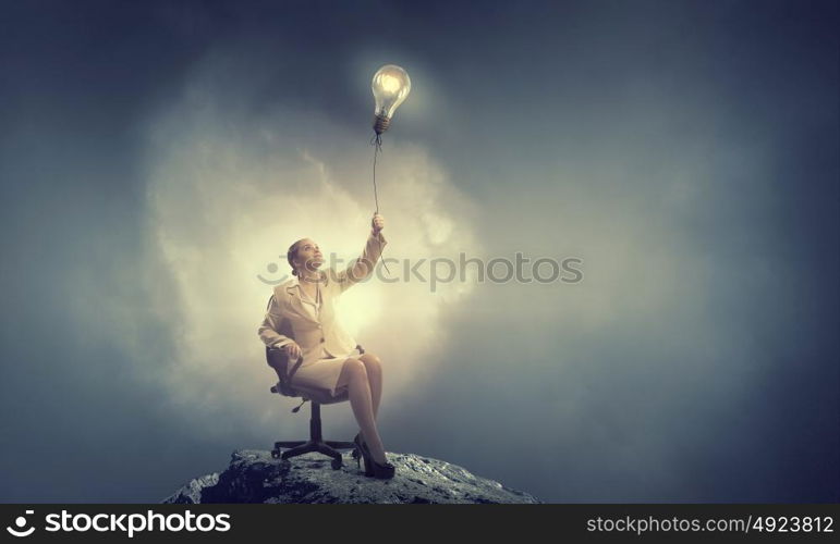 Waiting for inspiration to come. Young businesswoman sitting in chair with light bulb balloon