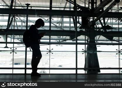 waiting in the airport, using smartphone, silhouette backpacker using technology