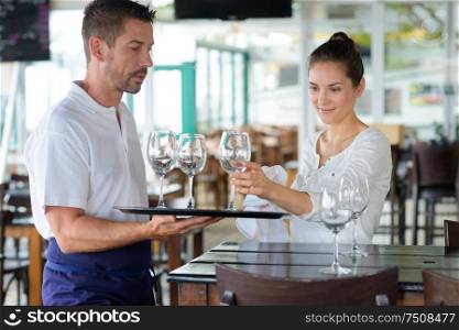 waitress and waiter cleaning glasses in a restaurant