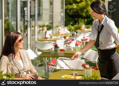 Waitress giving back to woman change money bill restaurant terrace