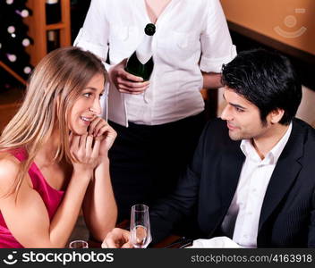 Waitress in a fancy restaurant filling glasses of couple with champagne