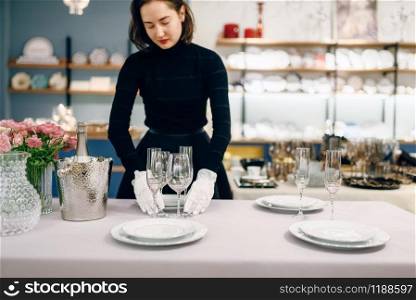 Waitress in gloves puts the dishes for dining, table setting. Serving service, festive dinner decoration, holiday dinnerware