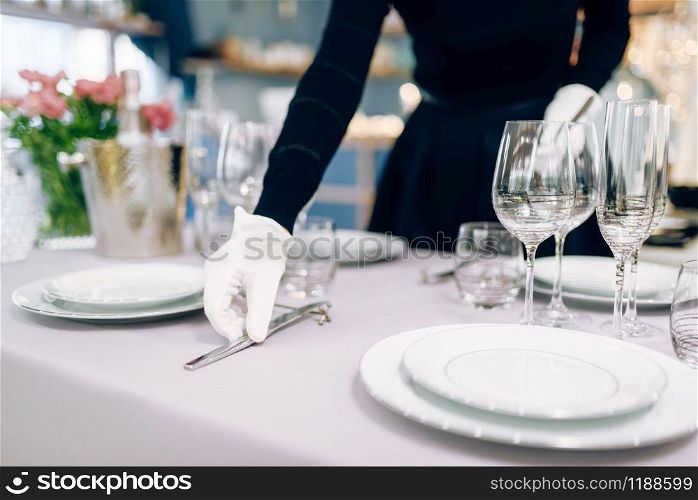 Waitress in gloves puts the knife, table setting. Serving service, festive dinner decoration, holiday dinnerware