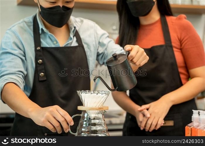 Waitress prepares cappuccino wearing protective face mask in a cafe,Coronavirus has turned into a global emergency.