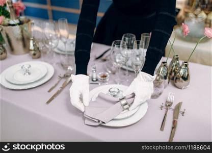 Waitress prepares tablecloth, table setting. Serving service, festive dinner decoration, holiday dinnerware, tableware