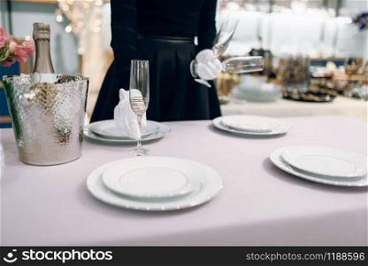 Waitress puts the glasses for dining, table setting. Serving service, festive dinner decoration, holiday dinnerware