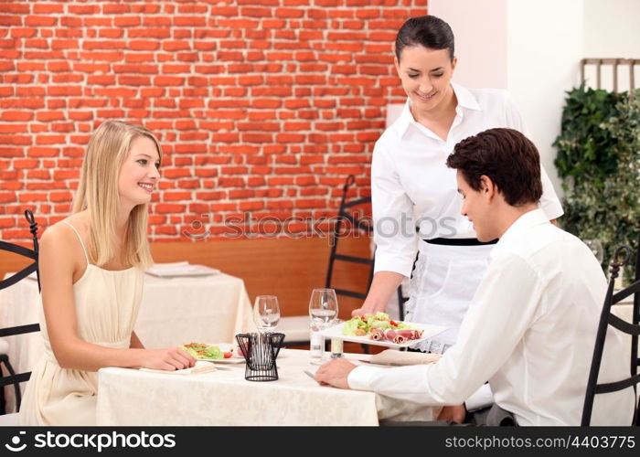 Waitress serving a young couple in a restaurant