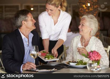 Waitress Serving Food To Senior Couple In Restaurant