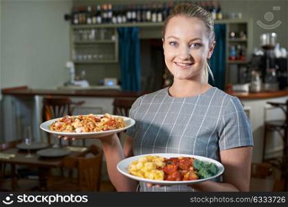 Waitress Serving Plates Of Food In Restaurant