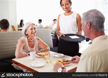 Waitress Serving Senior Couple Breakfast In Hotel Restaurant