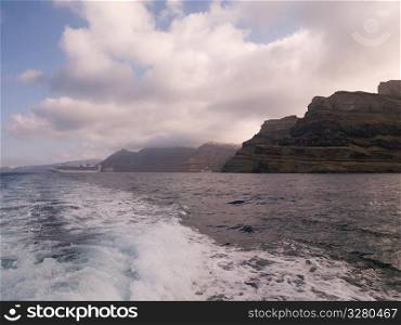 Wake of ship along Santorini shoreline