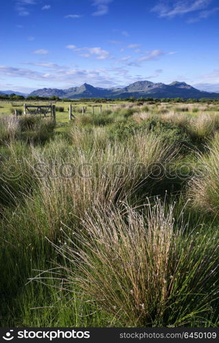 Wales, Gwynedd, Porthmadog. Looking towards Snowdonia mountain range from Porthamdog Cob during a summer sunset.. Looking towards Snowdonia mountain range landscape during a summer sunset