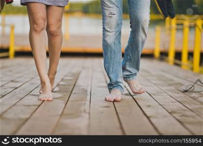 Walk barefoot in nature.. Bare male and female feet are on the footbridge of the lake pier 6545.
