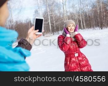 Walk in winter park. Young man in winter park making photo of his girlfriend