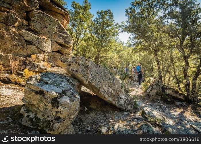 Walkers pass large boulders on the Scala di Santa Regina trail near Corscia in Corsica