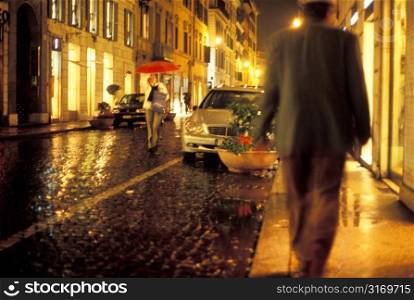 Walking Along A Narrow Cobblestone Street In The Rain