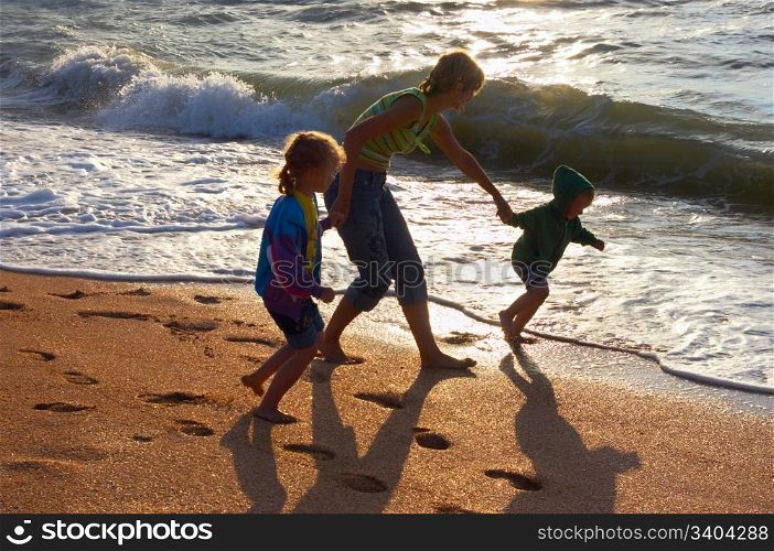 Walking family on evening sandy beach and surf