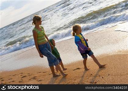 Walking family on sandy beach and surf