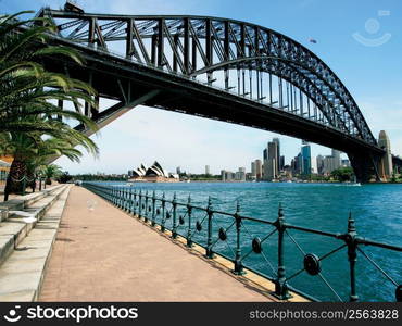 Walking on the path that leads beneath the Sydney Harbour Bridge in Australia. Cityscape of Sydney behind.