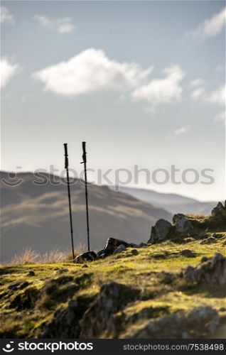 Walking poles and backpack on ground of hills in Lake District iwth mountains and bright Autumn Fall sky hiting landscape in background