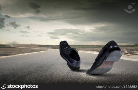 Walking shoes. Pair of black shoes walking on road