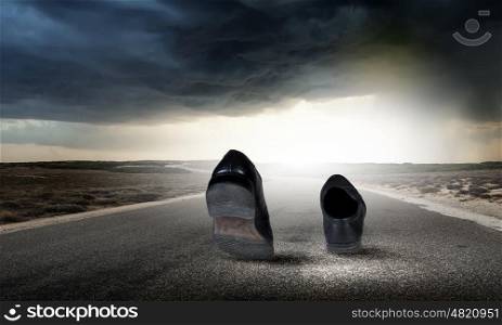 Walking shoes. Pair of black shoes walking on road