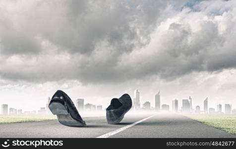 Walking shoes. Pair of black shoes walking on road